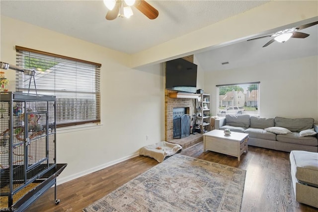 living area with a ceiling fan, baseboards, wood finished floors, and a fireplace