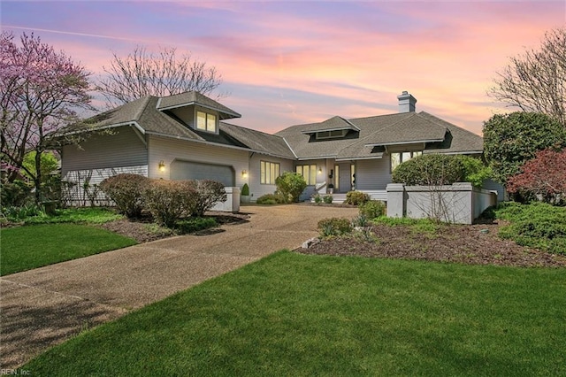 view of front facade with a front yard, driveway, an attached garage, a chimney, and a porch