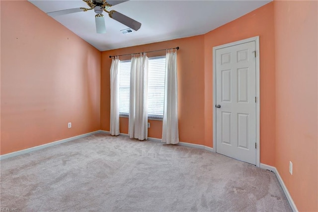 carpeted spare room featuring ceiling fan and baseboards