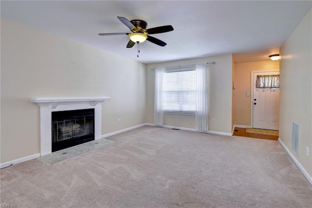 unfurnished living room featuring carpet, a fireplace with flush hearth, a ceiling fan, and baseboards