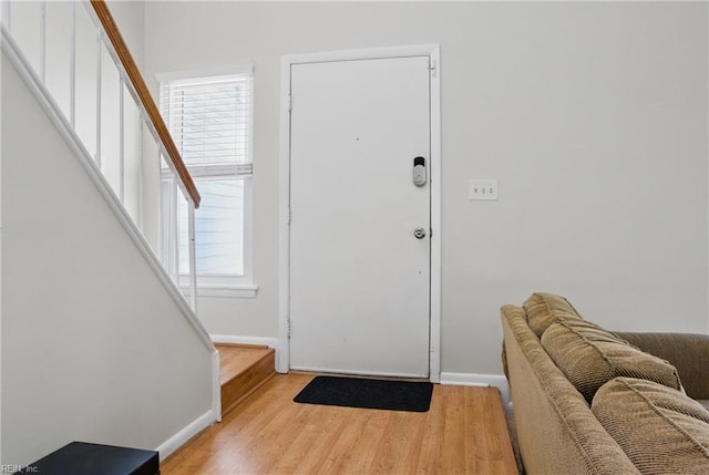 foyer entrance with baseboards, wood finished floors, and stairs