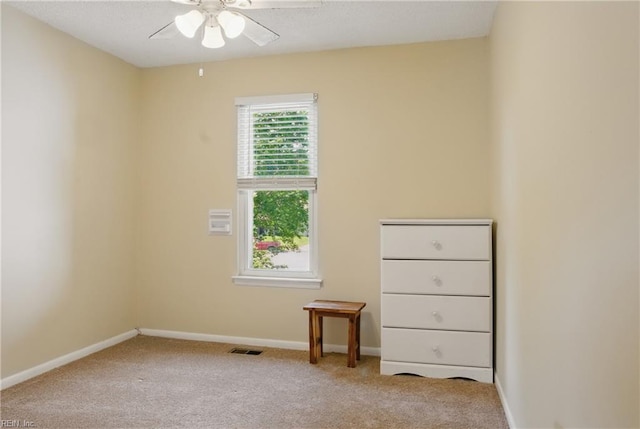 carpeted spare room featuring a ceiling fan and baseboards