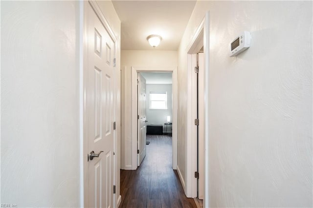 corridor featuring baseboards and dark wood finished floors