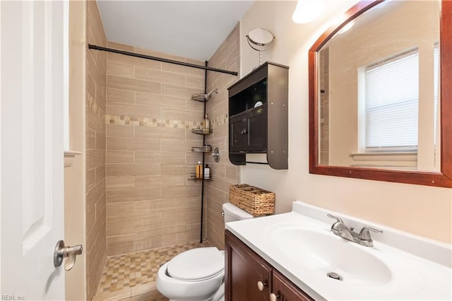 bathroom with vanity, a tile shower, and toilet