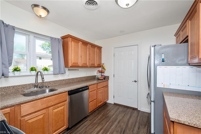 kitchen featuring appliances with stainless steel finishes, a sink, brown cabinetry, dark wood-type flooring, and visible vents