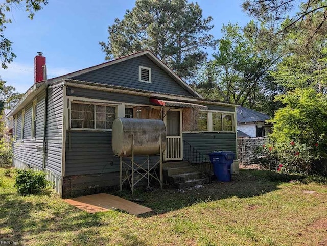 back of house with heating fuel, a yard, a chimney, and entry steps
