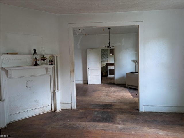 hall featuring baseboards, wood finished floors, and a chandelier