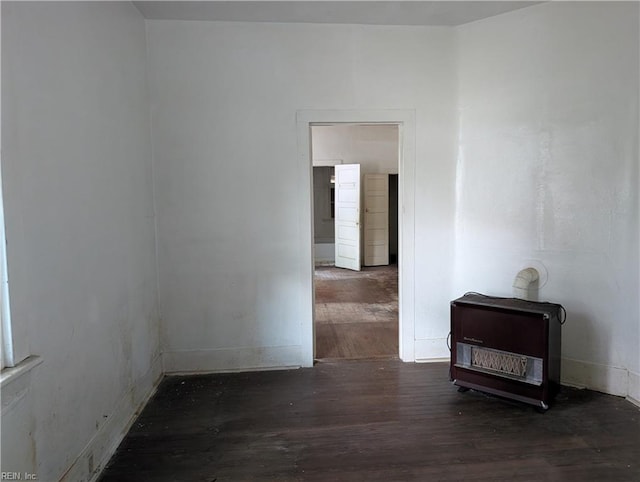 unfurnished room featuring baseboards, heating unit, and wood finished floors