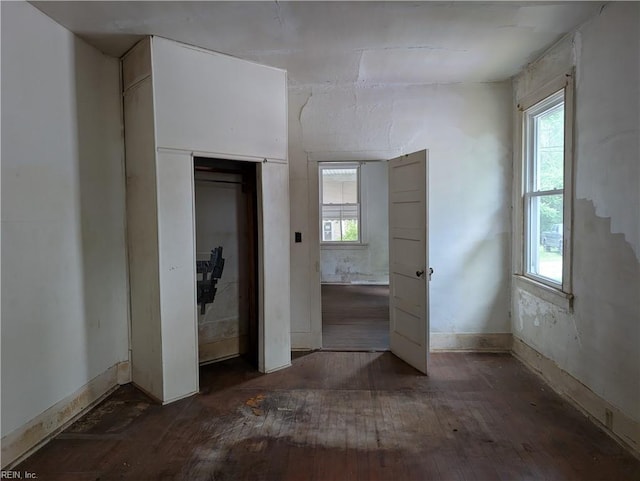 unfurnished bedroom featuring multiple windows, a closet, and hardwood / wood-style floors