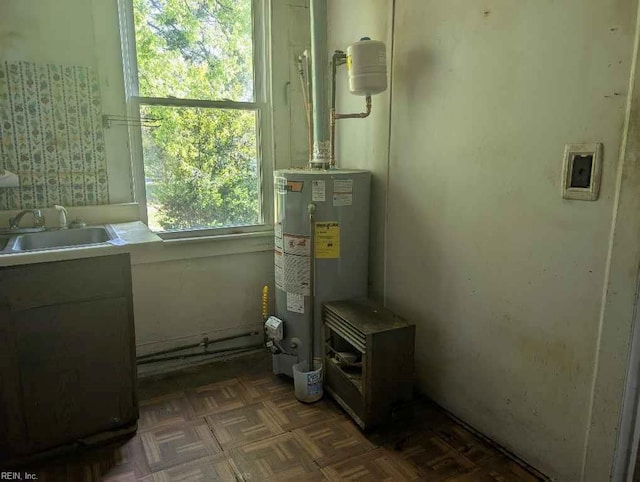 utility room with water heater and a sink