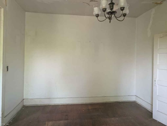 unfurnished dining area featuring baseboards, wood finished floors, and a notable chandelier