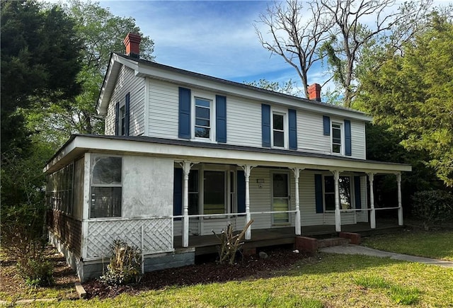farmhouse inspired home featuring a porch, a chimney, and a front yard