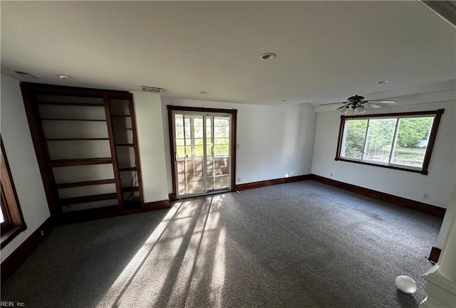 empty room with dark carpet, baseboards, and plenty of natural light