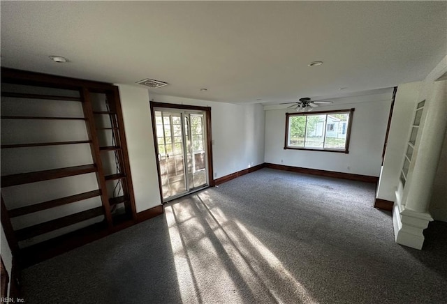spare room with baseboards, visible vents, ceiling fan, and dark colored carpet