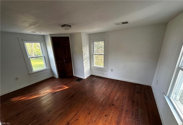 unfurnished bedroom featuring baseboards, dark wood-style floors, and multiple windows