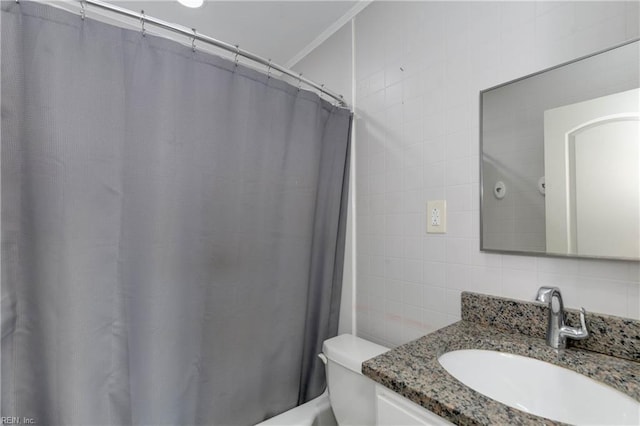 bathroom with crown molding, vanity, toilet, tile walls, and tasteful backsplash
