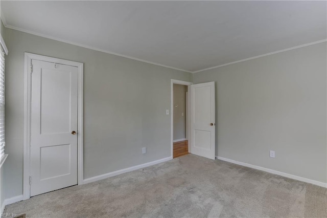 unfurnished bedroom featuring carpet flooring, crown molding, and baseboards