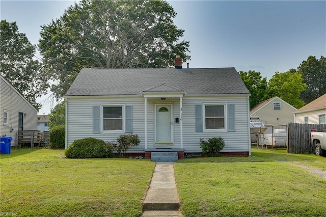 bungalow-style house with roof with shingles, fence, and a front yard