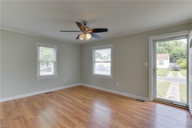 spare room featuring visible vents, ornamental molding, a healthy amount of sunlight, and light wood-style floors