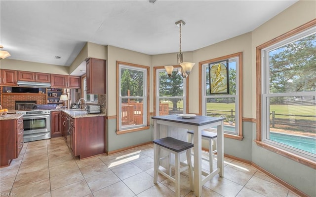 kitchen featuring a sink, stainless steel electric stove, plenty of natural light, and light tile patterned floors