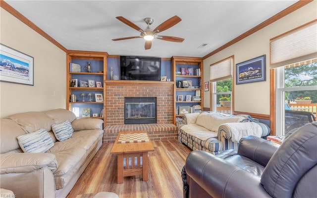 living room with crown molding, a fireplace, a ceiling fan, and visible vents