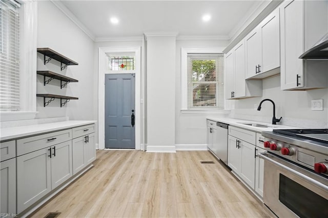 kitchen featuring open shelves, light countertops, a sink, light wood finished floors, and appliances with stainless steel finishes