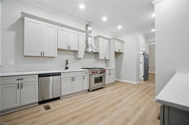 kitchen with visible vents, crown molding, wall chimney range hood, a sink, and appliances with stainless steel finishes
