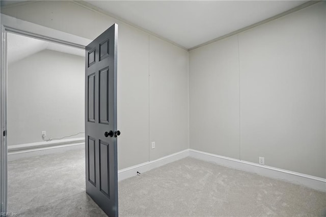 spare room with baseboards, vaulted ceiling, and carpet