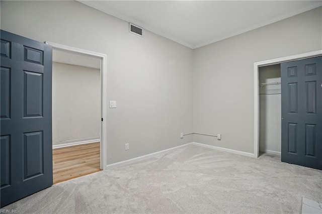 unfurnished bedroom with carpet, baseboards, visible vents, ornamental molding, and a closet