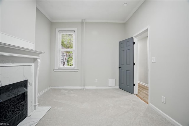 unfurnished living room featuring a fireplace with flush hearth, baseboards, ornamental molding, and carpet