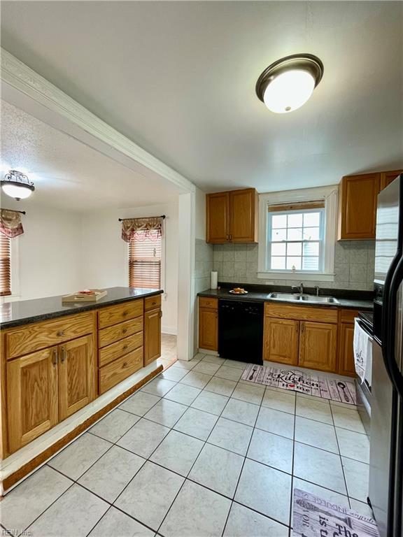 222 Chesterfield Rd, Hampton, VA 23661 - kitchen with black appliances, a sink, dark countertops, light tile patterned flooring, and tasteful backsplash