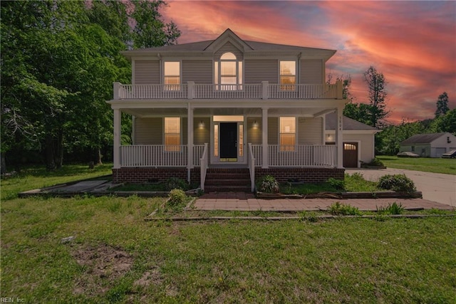 view of front facade featuring a porch, concrete driveway, a balcony, and a front yard
