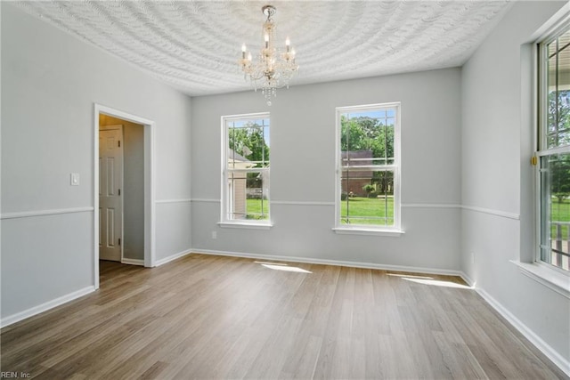unfurnished dining area featuring baseboards, a notable chandelier, and wood finished floors