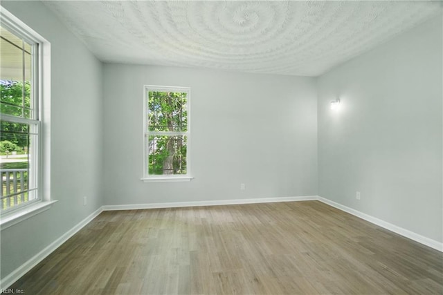 spare room featuring a textured ceiling, baseboards, and wood finished floors