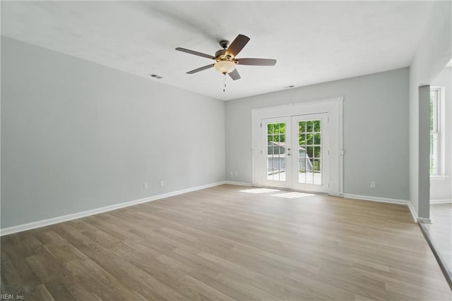 spare room featuring baseboards, ceiling fan, french doors, and light wood finished floors