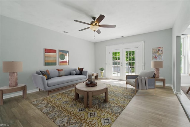 living area featuring french doors, a ceiling fan, light wood-style flooring, and baseboards