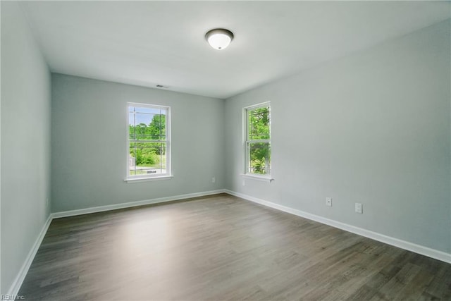 spare room featuring baseboards, dark wood finished floors, and visible vents
