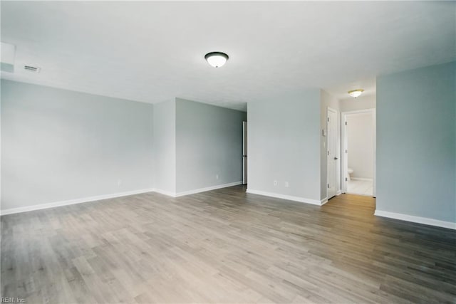spare room with visible vents, baseboards, and wood finished floors