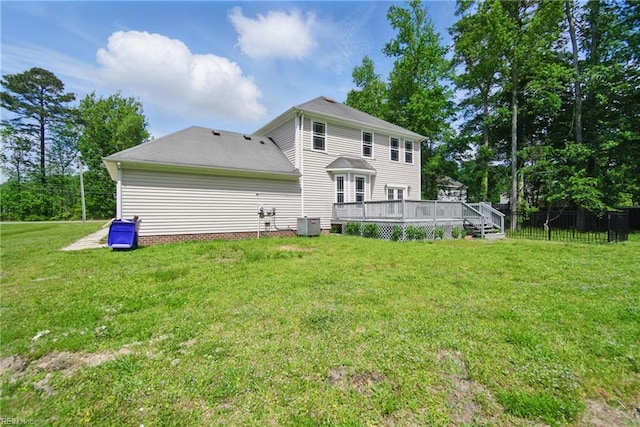 rear view of property with a lawn, a wooden deck, central air condition unit, and fence