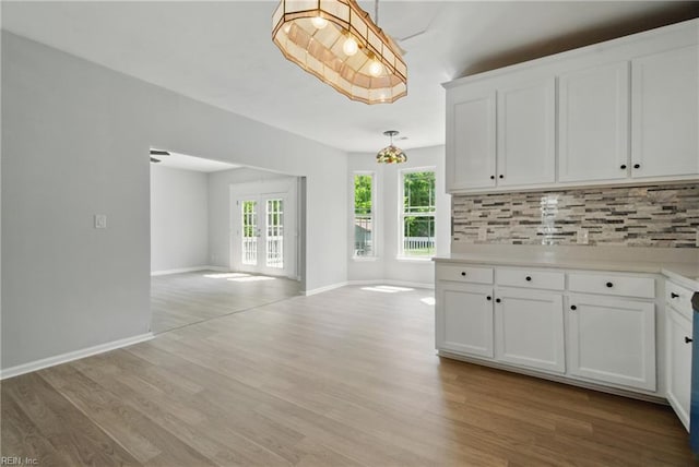 kitchen featuring white cabinets, tasteful backsplash, light countertops, open floor plan, and light wood-type flooring