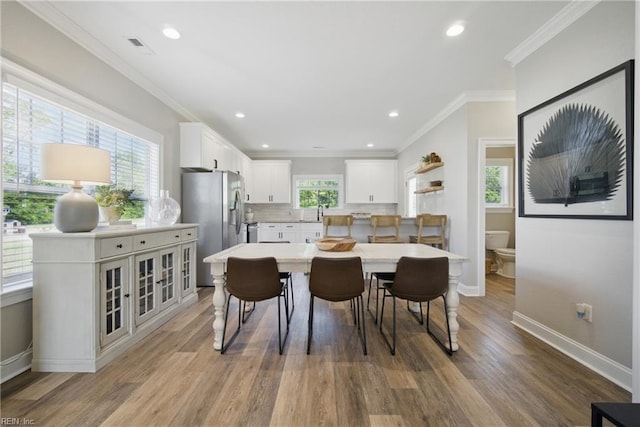 dining area with light wood-style floors, recessed lighting, baseboards, visible vents, and ornamental molding
