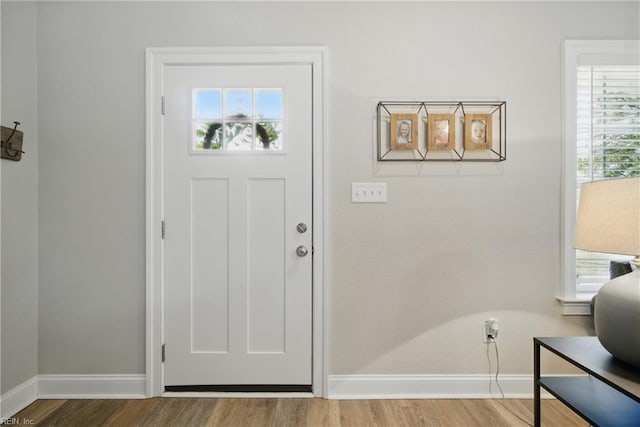 doorway to outside featuring baseboards and wood finished floors