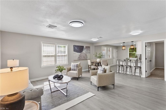 living area featuring baseboards, visible vents, and wood finished floors