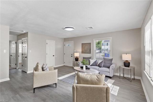 living room featuring visible vents, baseboards, and wood finished floors