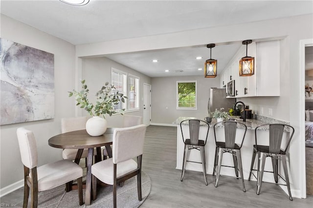 dining area with light wood-type flooring, recessed lighting, and baseboards