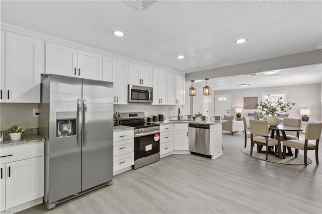 kitchen with open floor plan, a sink, appliances with stainless steel finishes, and white cabinets
