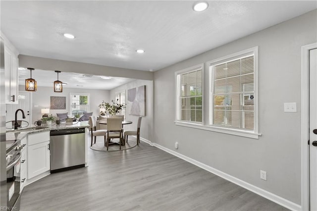 kitchen featuring appliances with stainless steel finishes, a sink, white cabinetry, baseboards, and recessed lighting