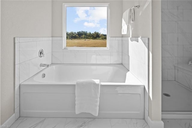 bathroom featuring a garden tub, marble finish floor, baseboards, and a shower stall