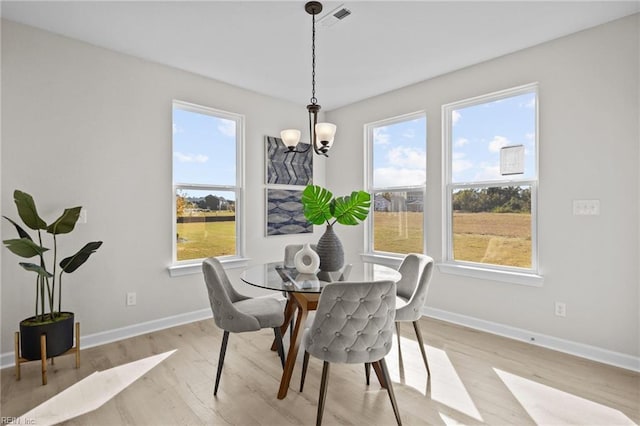 dining space featuring an inviting chandelier, light wood-style flooring, baseboards, and visible vents