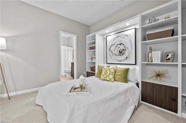 bedroom with baseboards, carpet flooring, and ensuite bath